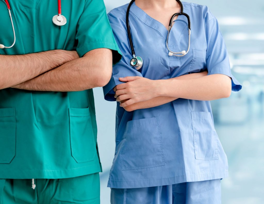 Male and female doctors in a hospital with crossed arms.
