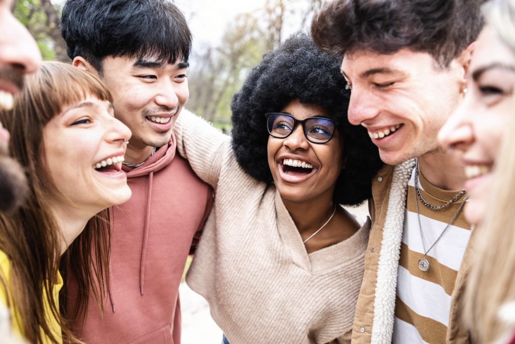 Happy young people hugging each other in a group.