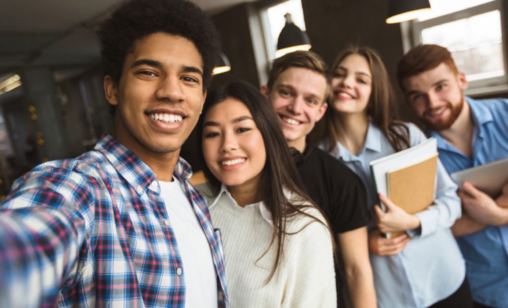 A group of teenagers taking a selfie in a classroom.