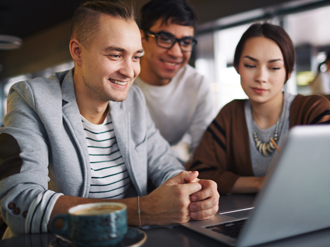 A group of young people huddled around a computer looking at the Up to Me Resources