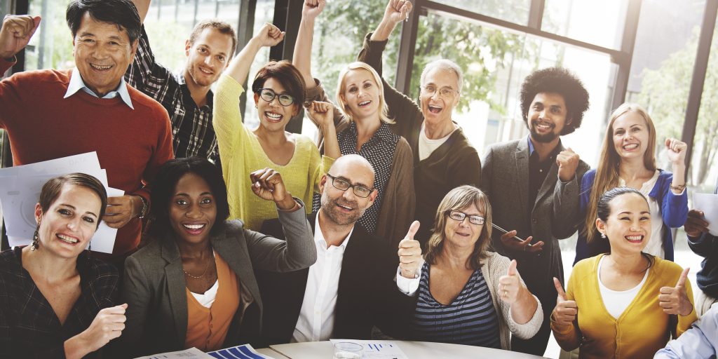 A diverse group of cheerful individuals, holding papers, giving thumbs up and raising their fists in celebration