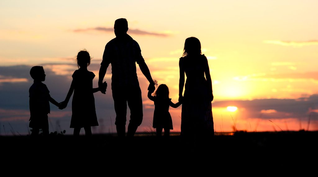 A silhouette of a family with the sunrising in the background.