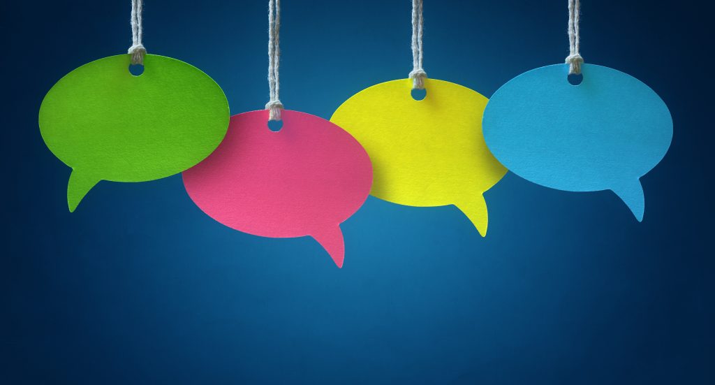 Blank colorful speech bubbles hanging from a cord over blue background.