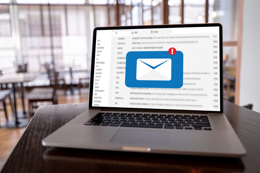 Open laptop on a wooden table displaying an email interface with a prominent envelope icon.