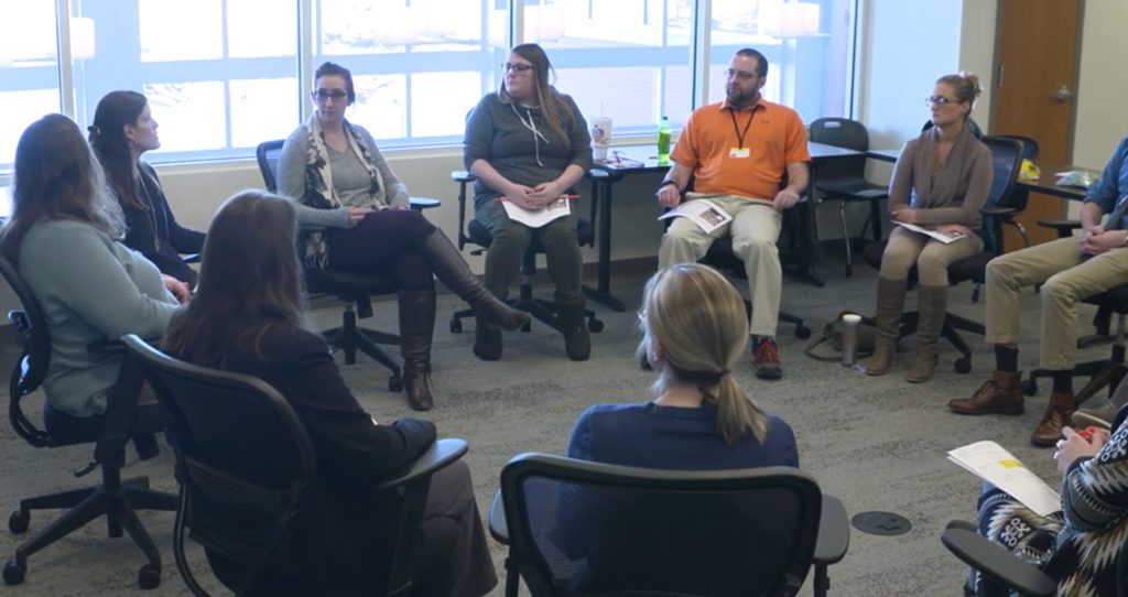 Group gathered in circle participating in the Compassion Resilience Toolkit.