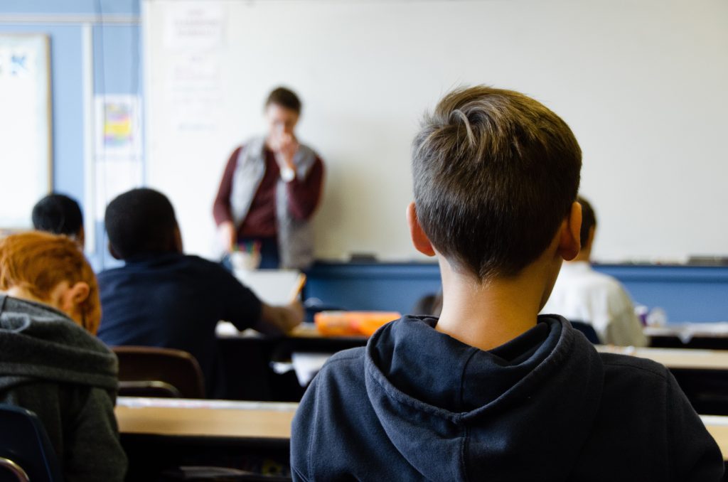 Students sitting in a classroom who is attentively listening to a teacher.